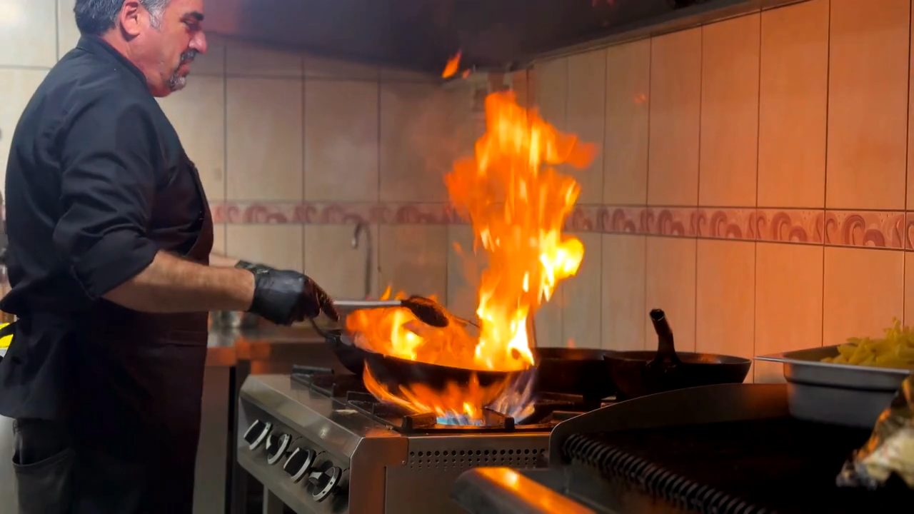 A chef flambéing in a restaurant kitchen