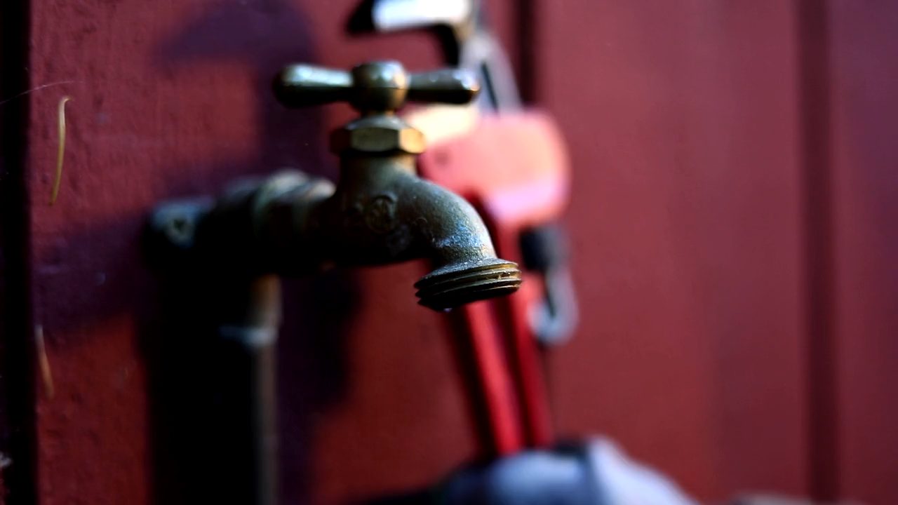 A plumber tightening a fitting on an outdoor spigot